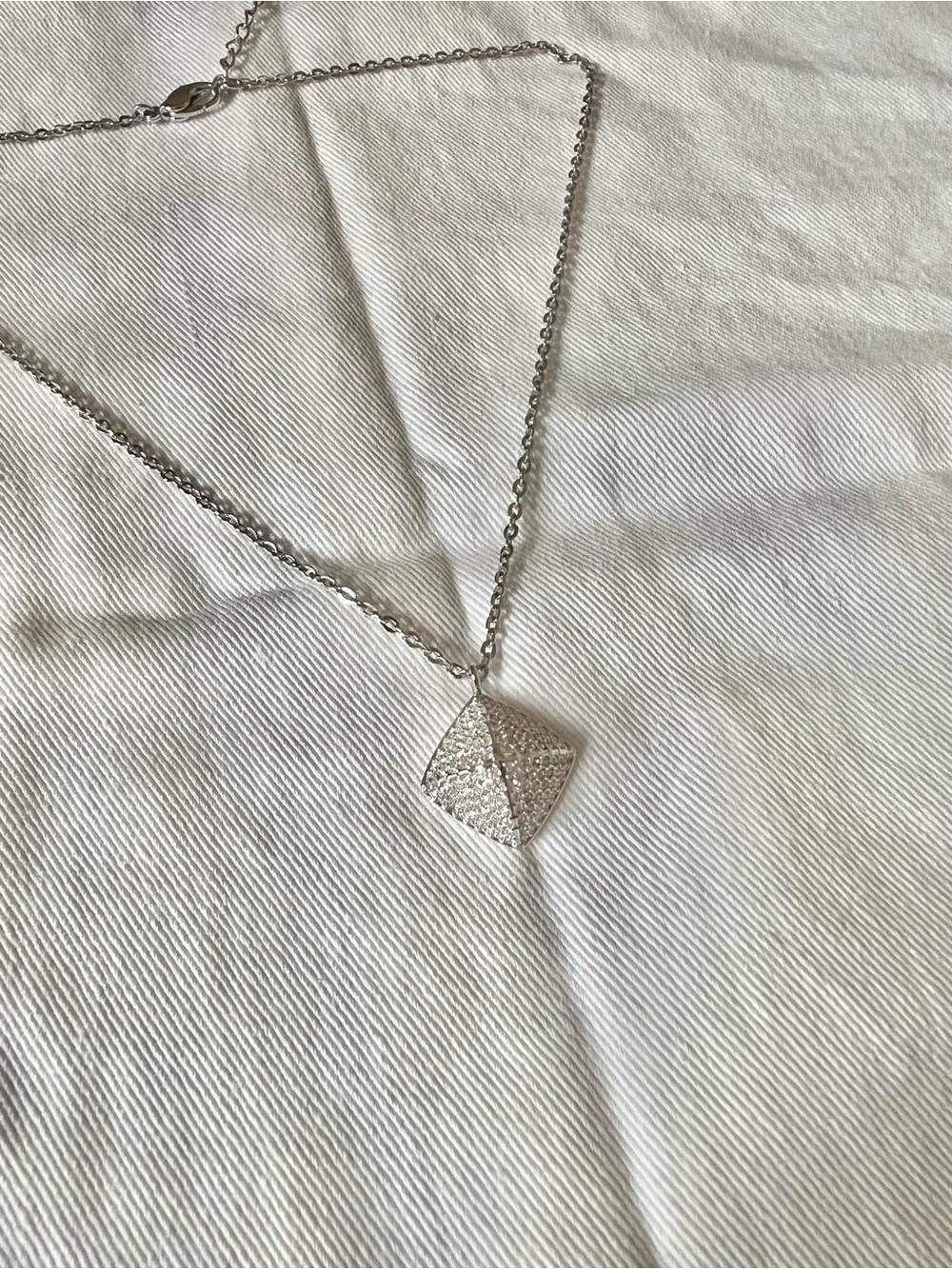 Silver pendant necklace with textured, diamond-cut surfaces